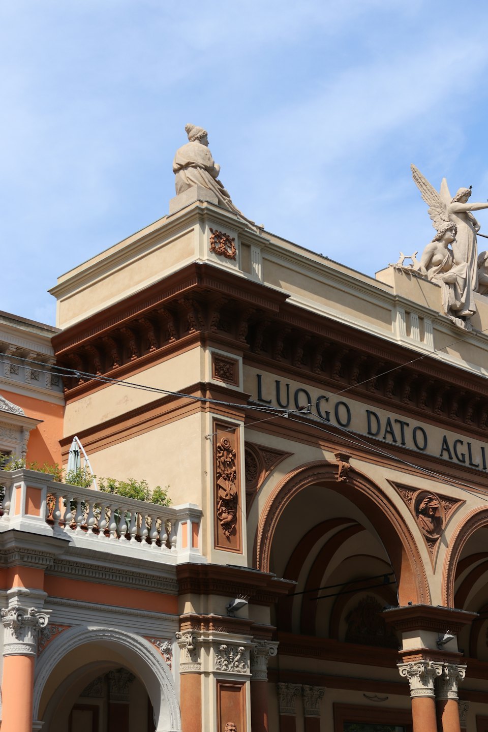 Edificio storico ornato con colonne decorative e statue in pietra sul tetto.